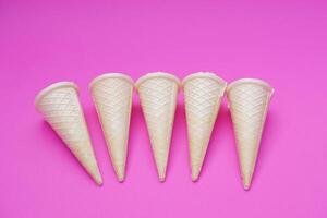 Empty crispy waffle ice cream cones isolated on pink background. Concept, part of pattern of ice creams in cone shape. Snack and dessert. copy space for text. photo