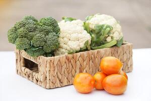 Basket of organic vegetables from garden. Broccoli, cauliflower and tomatoes. Outdoor background. Concept, food ingredient. Healthy eating, source of vitamins, fiber and nutritions. Fresh from garden. photo