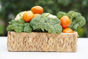 Basket of organic vegetables from garden. Broccoli, cauliflower and tomatoes. Outdoor background. Concept, food ingredient. Healthy eating, source of vitamins, fiber and nutritions. Fresh from garden. photo
