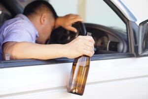 Drunk man holds beer bottle in car. Concept , Campaign for don't drive, don't drink alcohol that can cause car accident and illegal. Dangerous driving when drunk. photo