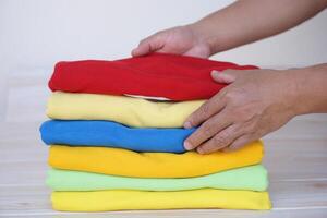 Close up hands hold and arrages stack of folded clothes. after doing laundry. Concept, daily chore, household. Folded clothes for neat and clean. Maintenance and keep garments for sanitary. photo