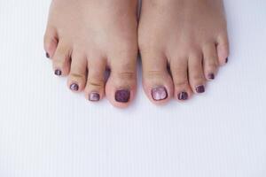 Close up polished nails and toes. White floor background. Concept, fashion and beauty on part of body. Nails polishment. photo