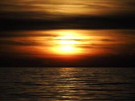 golden sun rays reflection on the sea at sunset photo