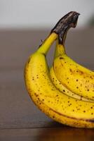 maduro plátano manojo con oscuro lugares en mesa 4 4 foto