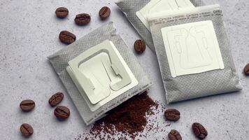 Drip coffee paper bags with coffee beans on a grey concrete background video