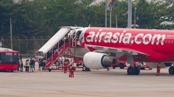 phuket, thailand, februari 27, 2023 - airasia jet flygplan i phuket flygplats. människor styrelse ett flygplan. flygplan på de flygfält, trappa. resa begrepp video