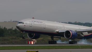 Moskva, ryska federation - juli 29, 2021. boeing 777 av aeroflot flygbolag landning, rörande de landningsbana, rök när bromsning från de chassi. de flygplan är som heter anton Tjechov. begrepp flyg video