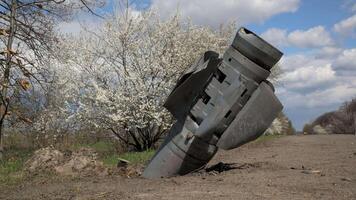 un no explotado militar misil de el ruso Ejército en el lado de el la carretera en contra el fondo de un floración árbol. Consecuencias de ruso agresión en contra Ucrania en 2022 video