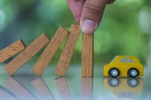 Car insurance Insurance. Hands stop the effects wooden blocks from falling to car. photo