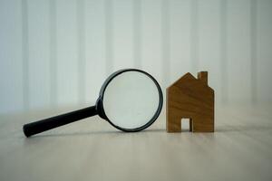 Wood house and magnifying glass. Symbol of find real estate. photo