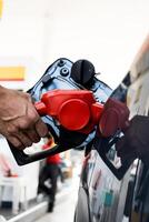 Refueling car with gasoline at gas station. Man hand grips a gasoline fuel nozzle at the refuel gas station station. photo