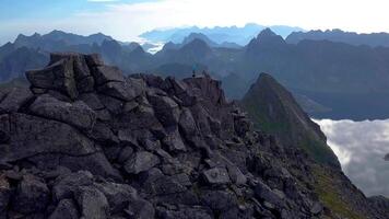 Aerial view of Man and woman at the top of the mountain. Beautiful view of the peaked tops of the Lofoten Islands. Norway 4k video