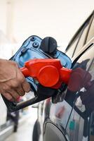 Refueling car with gasoline at gas station. Man hand grips a gasoline fuel nozzle at the refuel gas station station. photo