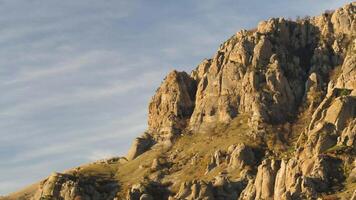 Aerial for a beautiful mountain in the sunny evening on a blue sky background. Shot. Steep rocks in profile in autumn sunny evening on cloudy blue sky background. video