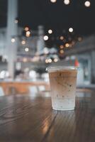 un vaso de con hielo latté servido en el de madera mesa con bokeh ligero foto