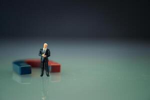 Miniature businessman stand with magnet. Business and leadership concept photo