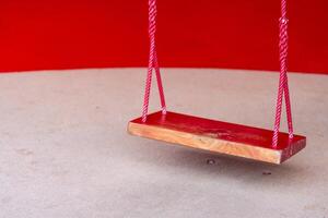 Wooden red swing for entertaining the smallest boys and girls photo