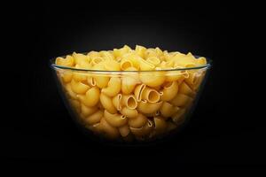 Pasta Pipe Rigate in a glass cup on black background photo