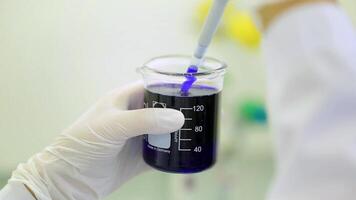 Close-up of glassware with blue fluid in scientist hand during medical test. Hands of clinician holding steel tools during scientific experiment in laboratory. test tubes and dropper video