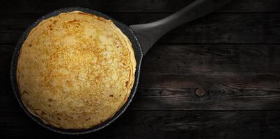 Homemade pancakes on a pan on a wooden plank photo