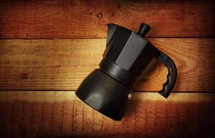 Black Italian coffee maker isolated on wooden background photo