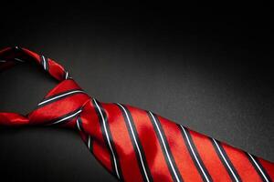 Red men's striped tie isolated on black background photo