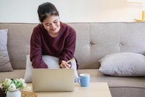 hermosa asiático mujer utilizando crédito tarjetas para compras en línea con laptops y teléfonos inteligentes, en línea compras retrato concepto. foto