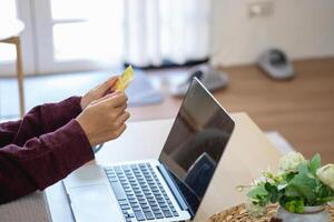 hermosa asiático mujer utilizando crédito tarjetas para compras en línea con laptops y teléfonos inteligentes, en línea compras retrato concepto. foto