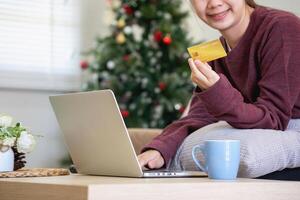hermosa asiático mujer utilizando crédito tarjetas para compras en línea con laptops y teléfonos inteligentes, en línea compras retrato concepto. foto