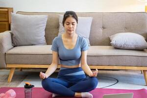 Healthy young woman doing breathing exercises at home, beautiful woman meditating at home with eyes closed, practicing yoga, doing pranayama techniques Mindfulness meditation concept photo