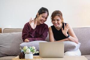 Relaxed young Asian woman enjoying relaxation on a comfy sofa at home. The beautiful girl calmly relaxes and breathes fresh air in the house. Watch movies and social networks. photo