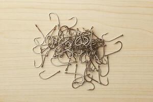 Close up, Pile of fish hooks on wooden background photo