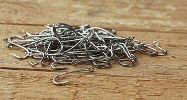 Close up, Pile of fish hooks on wooden plank background photo