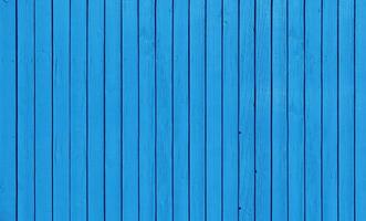 Wooden fence with parallel planks with blue paint. photo