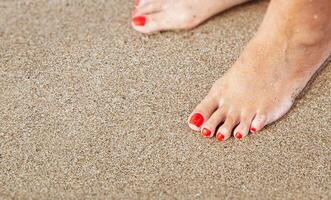 Women's feet with a pedicure in the sand on the beach photo