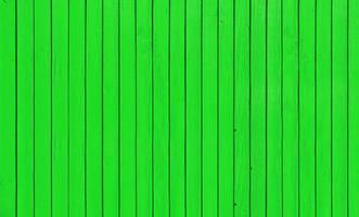 Wooden fence with parallel planks with green paint. photo