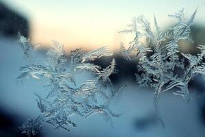 Frost pattern on window glass in winter cold blue light with orange glimpses of sunset. Christmas and New Year background. photo