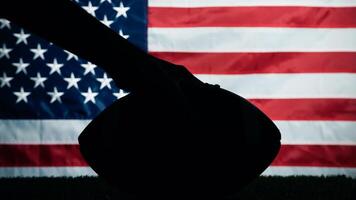 Hand holding Silhouette of American football ball against usa flag photo