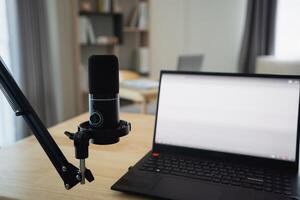 Close up view of worktable workplace with laptop and white screen, microphone for streaming or gaming, notebook, and decoration in home office room. Work at home place in the living room concept. photo