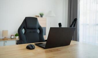 Close up view of worktable workplace with laptop and white screen, microphone for streaming or gaming, notebook, and decoration in home office room. Work at home place in the living room concept. photo