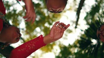 Two people making a pinky promise, shot from a low angle with blurred foliage in the background. video