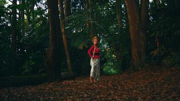 a woman exploring a forest at dusk, with a sense of adventure and curiosity, surrounded by tall trees and natural scenery. video