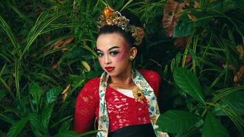 Serene woman in traditional attire surrounded by lush green foliage. video