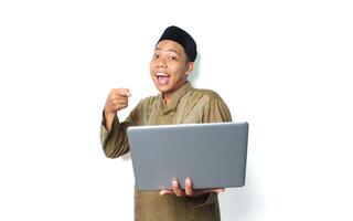 surprised asian muslim man pointing to laptop isolated on white background photo