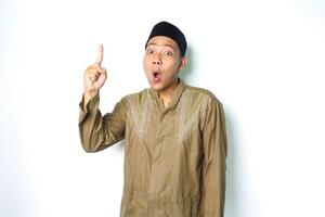 shocked asian muslim man pointing above isolated on white background photo