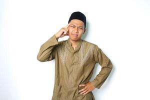 stressed asian muslim man wearing koko clothes hold his head feeling dizzy isolated on white background photo