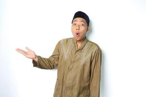 surprised asian muslim man presenting to the right side with open palm isolated on white background photo