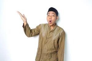 surprised asian muslim man presenting to above with open palm isolated on white background photo