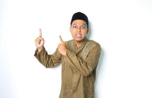 angry asian muslim man wearing arabic costume pointing up and look at camera isolated on white background photo