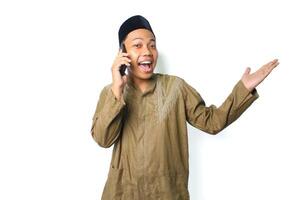 excited asian muslim man presenting empty space while talking using mobile phone isolated on white background photo